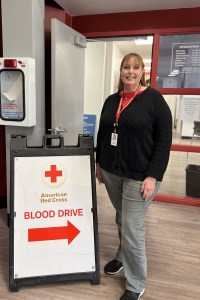Woman standing next to blood drive sign at a Red Cross Blood Donation Center in San Jose.